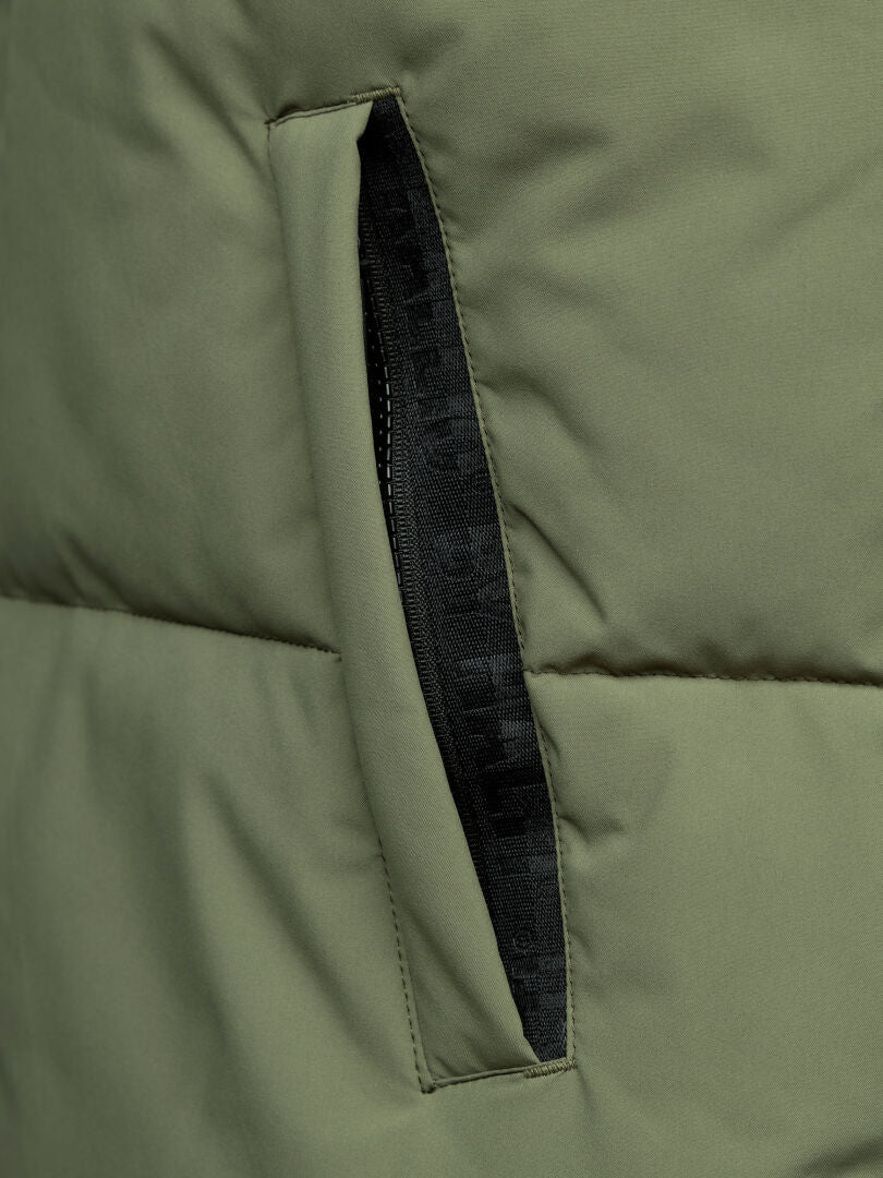Nahaufnahme einer grünen Halti Penger Classic Puffer Weste Herren mit einer teilweise offenen schwarzen Reißverschlusstasche.