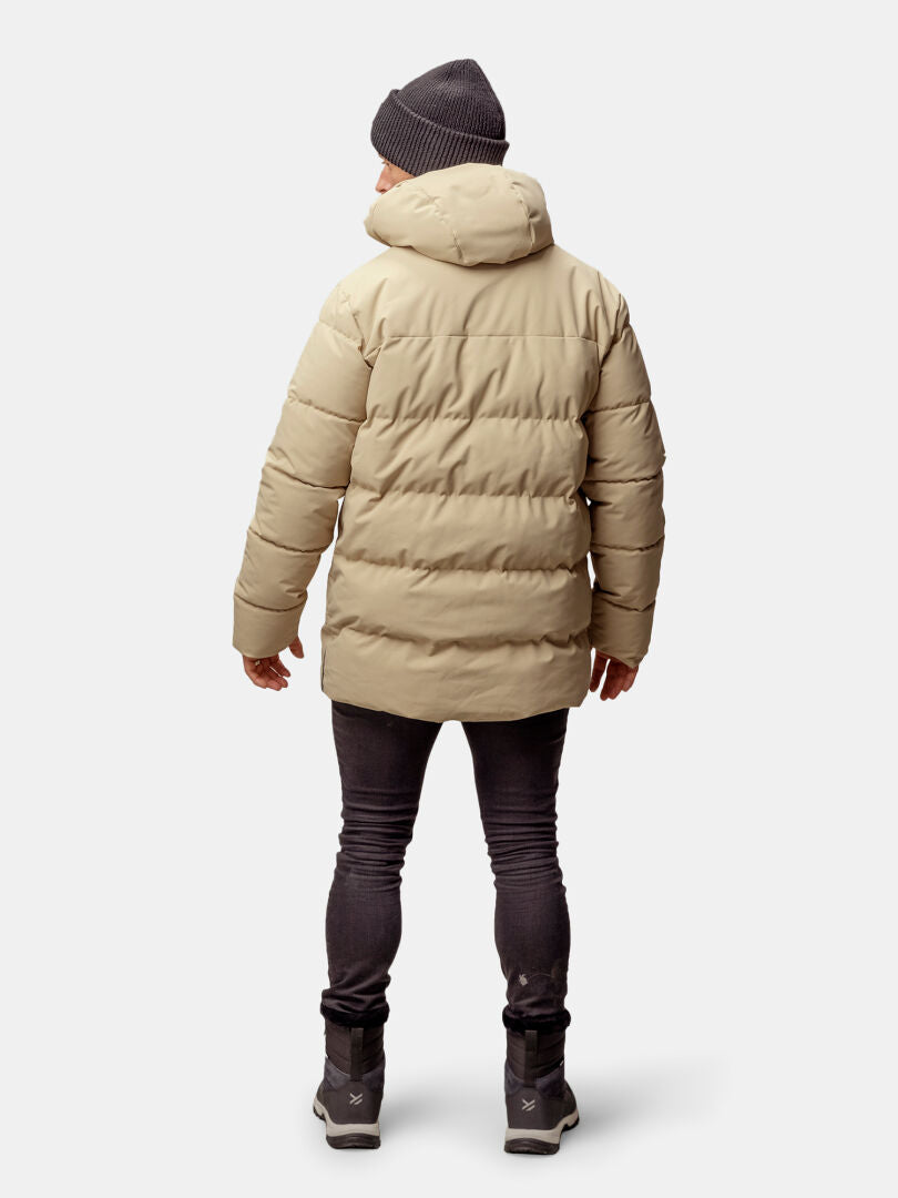 Person, die einen Halti Sammal Isolationsparka Herren in Beige, schwarze Jeans, graue Mütze und graue Schuhe trägt, von hinten gesehen.