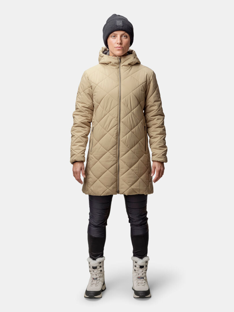 Person, die einen Halti Haapa Steppmantel Damen, eine schwarze Hose, eine graue Mütze und hellgraue Stiefel trägt und nach vorne schaut.