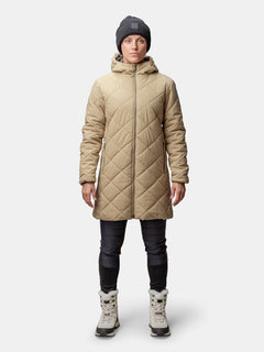 Person, die einen Halti Haapa Steppmantel Damen, eine schwarze Hose, eine graue Mütze und hellgraue Stiefel trägt und nach vorne schaut.