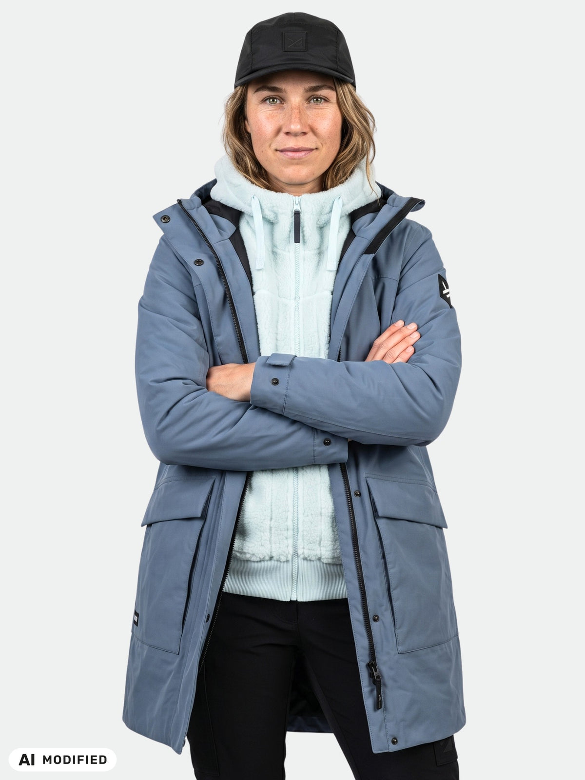 Eine Frau, die den „Halti Kortteli DX Insulated Parka Damen“ trägt, steht mit verschränkten Armen vor einem einfarbigen Hintergrund.