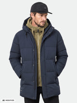 Mann in einem Halti Brahe Puffer-Parka, olivfarbenem Hoodie und schwarzer Mütze, die Hände in den Taschen; winddichter Herren-Winterlook.