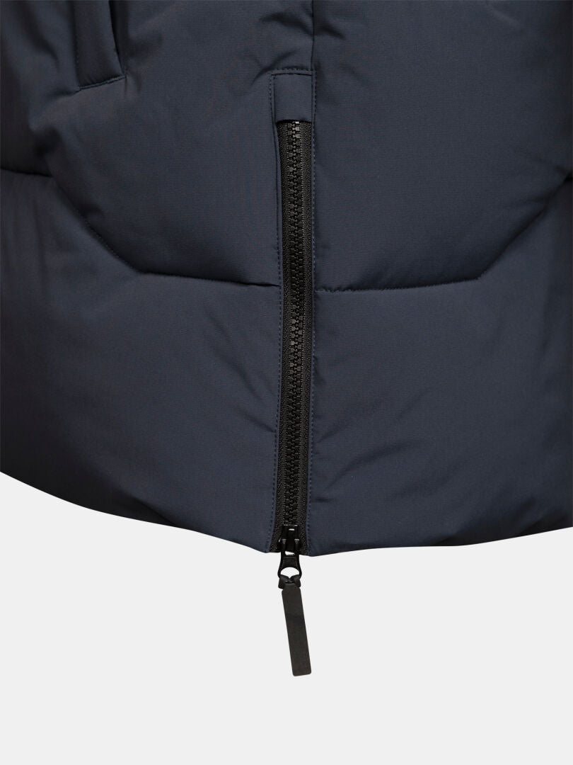 Nahaufnahme eines schwarzen Reißverschlusses an einem dunkelblauen „Halti Brahe Puffer Parka Herren“ mit DrymaxX-Zuglasche und sichtbaren Nähten.