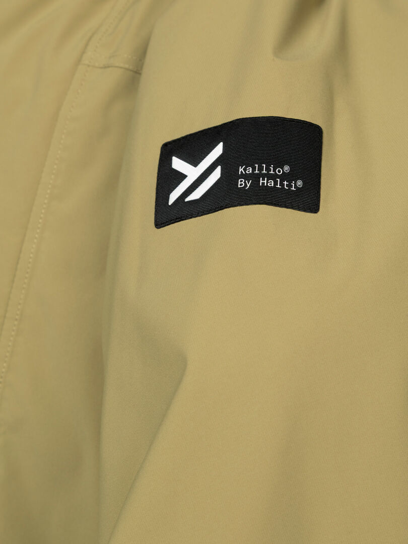 Tan Kortteli DX Parka von Halti mit schwarzem Etikett, weißem Logo und „Wetterschutz“ für zusätzlichen Schutz vor Wind und Wetter.