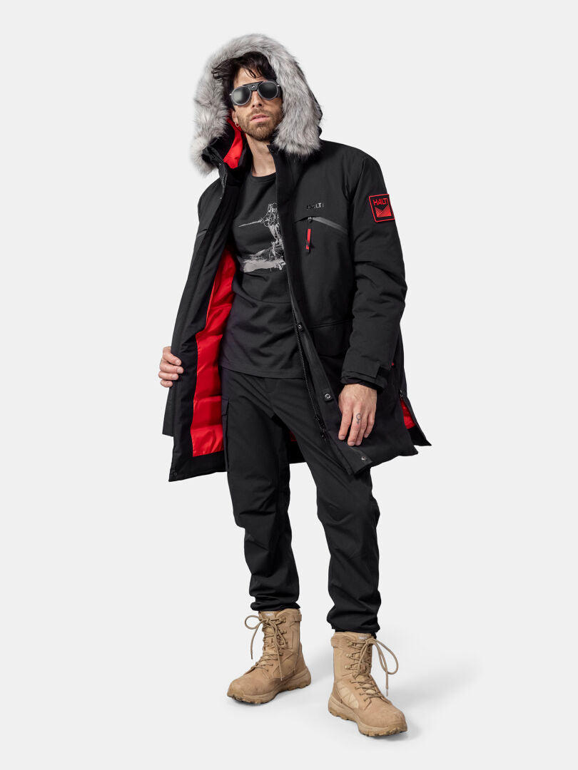 Ein Mann trägt den Halti 1976 Down Parka Unisex aus recyceltem Polyester vor einem schlichten Hintergrund.