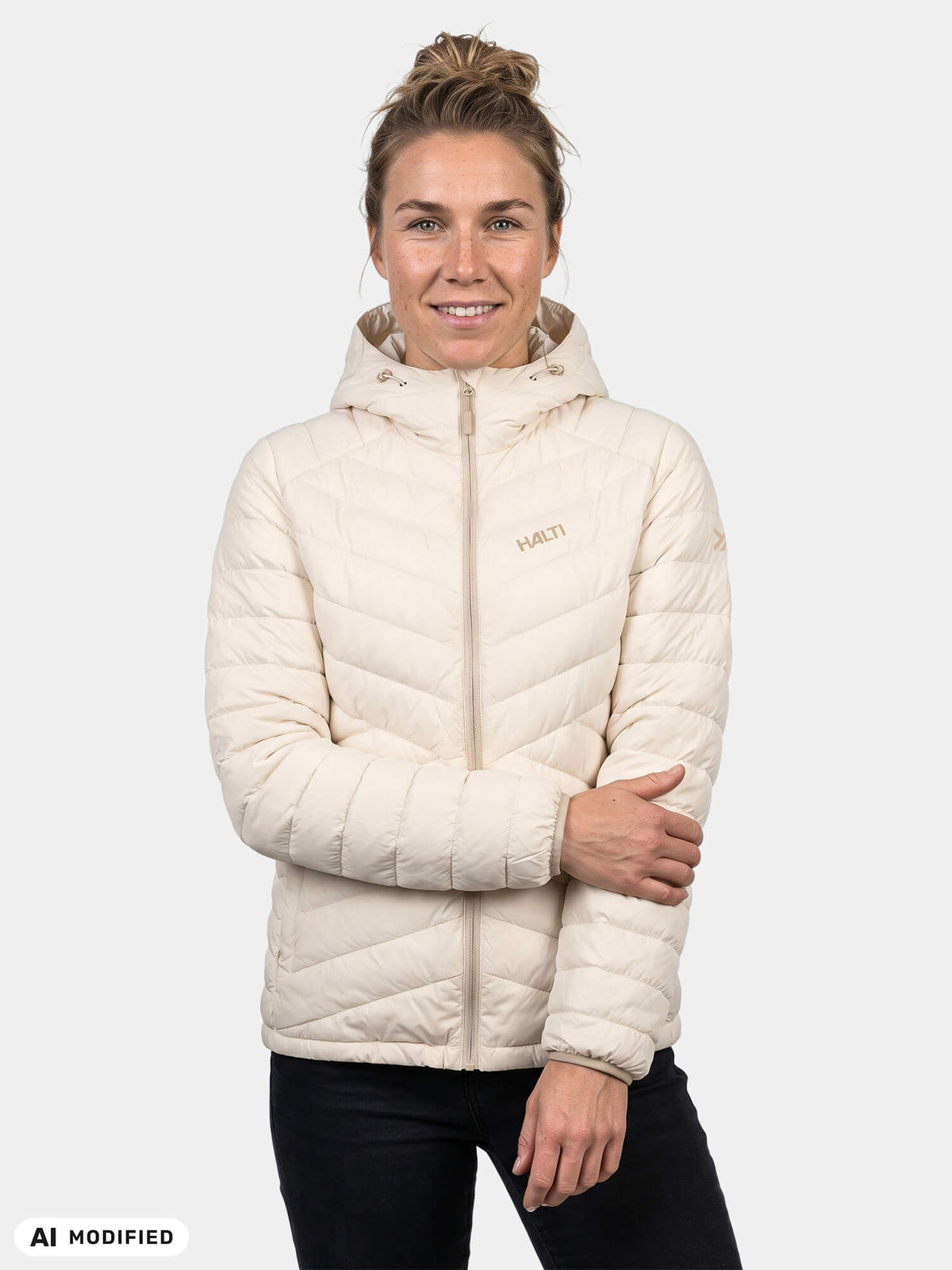 Eine Person, die eine cremefarbene Halti Huippu Untuvia Daunenjacke Damen – eine Daunenjacke mit Kapuze für Outdoor-Aktivitäten – trägt.