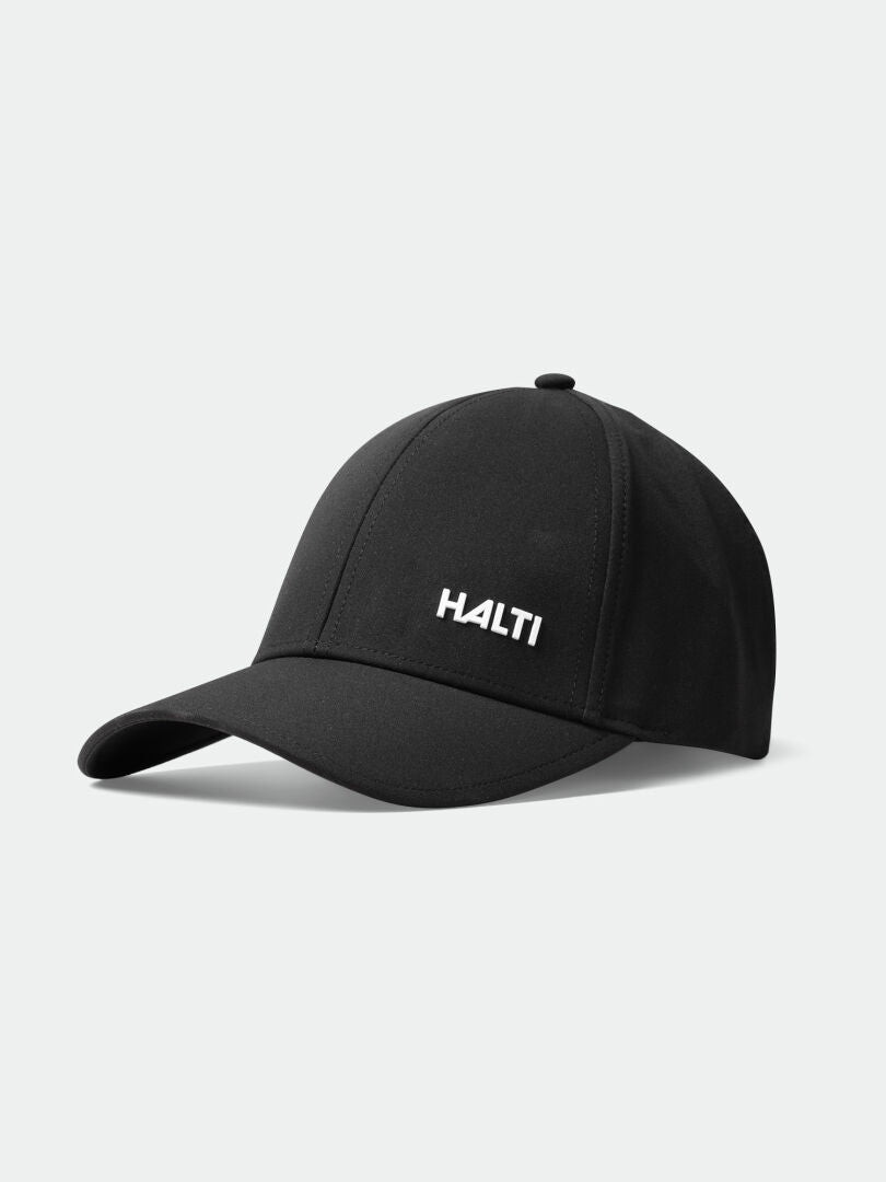 Die Halti Mattas Baseballkappe in Schwarz mit weißem Logo, aus Quick Dry Stretch-Gewebe, auf einfarbigem, hellem Untergrund.