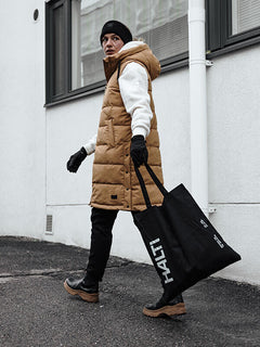 Person in hellbrauner Pufferweste, weißem Kapuzenpulli, schwarzer Mütze und Halti Viiri Fleece Handschuhen geht mit einer großen Tragetasche.