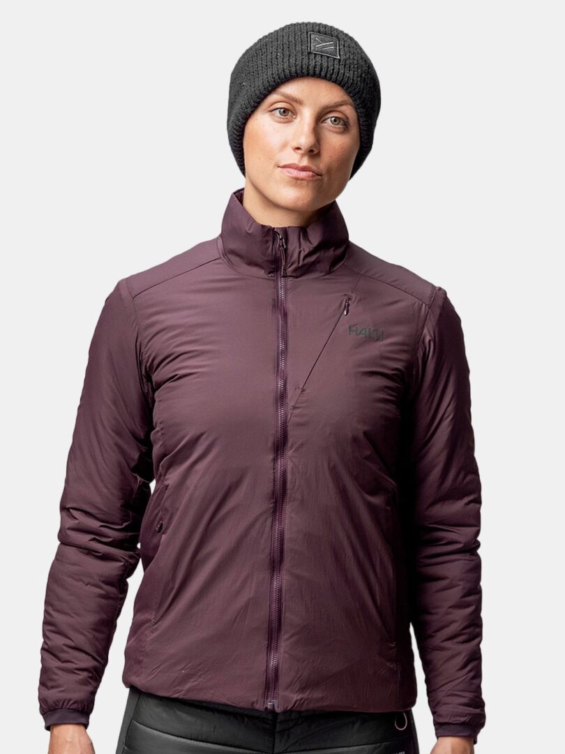 Eine Person in dunkelvioletter Jacke und grauem Halti Huurre Band steht vor einem schlichten hellen Hintergrund.