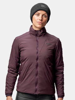 Eine Person in dunkelvioletter Jacke und grauem Halti Huurre Band steht vor einem schlichten hellen Hintergrund.