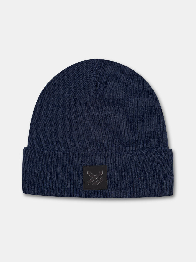 Die Halti Vataja Mütze ist eine marineblaue Strickmütze mit umgeschlagener Krempe und schwarzem, rechteckigem Aufnäher.