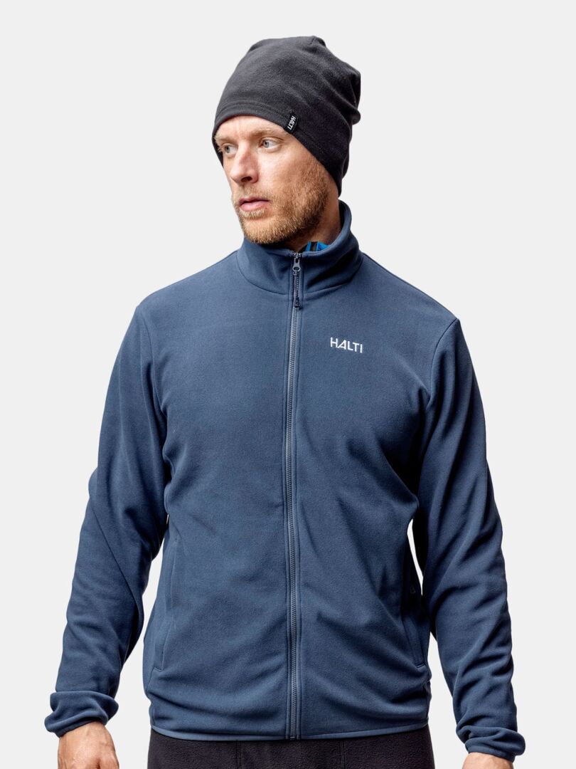 Mann in dunkelblauer Halti-Jacke und Trone-Fleece-Mütze, ideal zum Laufen oder Wintertraining vor hellem Hintergrund.