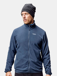 Mann in dunkelblauer Halti-Jacke und Trone-Fleece-Mütze, ideal zum Laufen oder Wintertraining vor hellem Hintergrund.