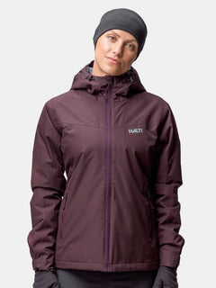 Eine Person in einer kastanienbraunen Kapuzenjacke und grauem Halti Trone Fleece Band steht vor einem hellen Hintergrund.