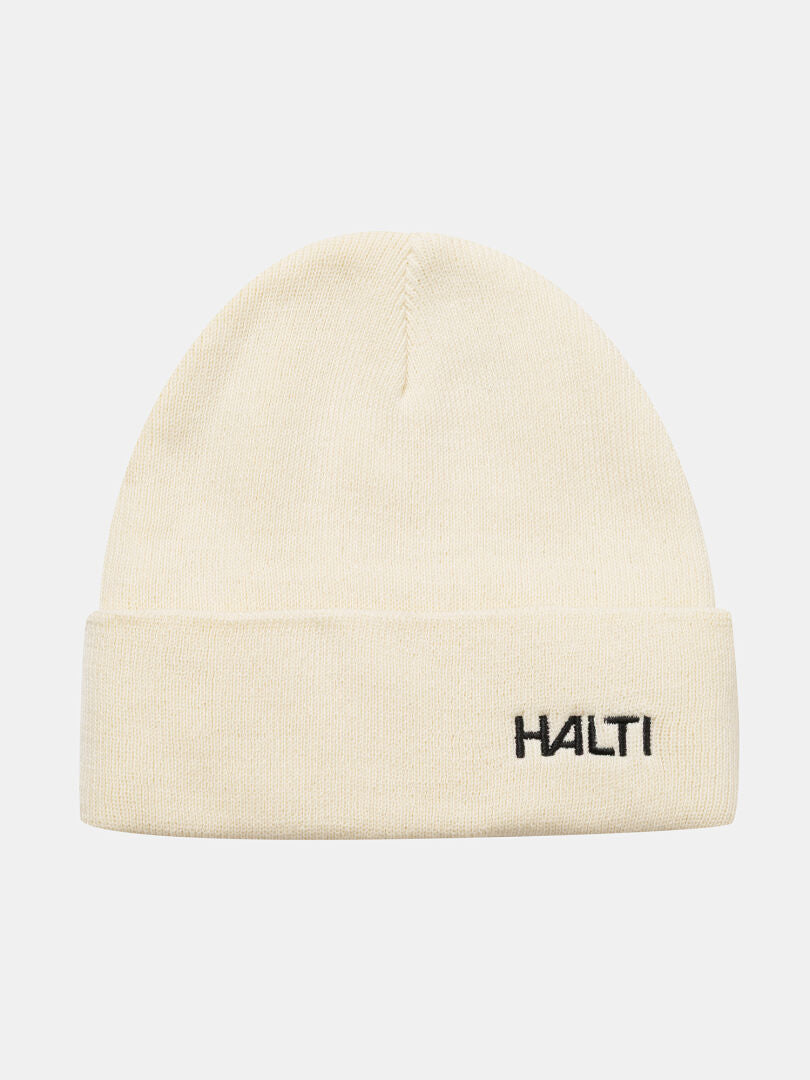Justie Mütze von Halti: Cremefarbene Strickmütze mit Fleecefutter, umgeschlagener Krempe und schwarzem Logo – perfekt für den Outdoor-Einsatz.