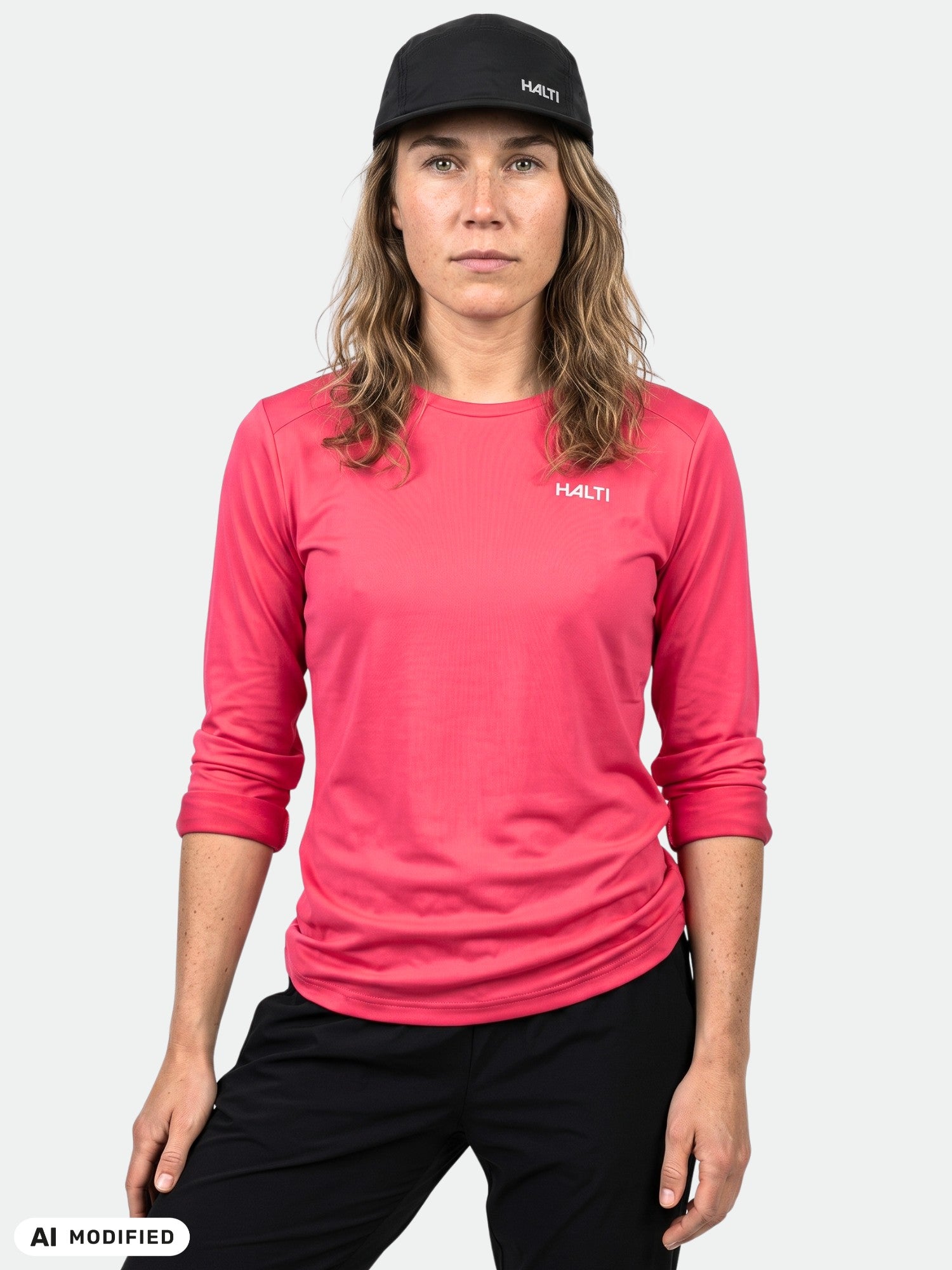Person in einem Trainingsshirt von Halti Salves für Damen (rosa), schwarzer Hose und schwarzer Mütze vor einem einfarbigen Hintergrund.