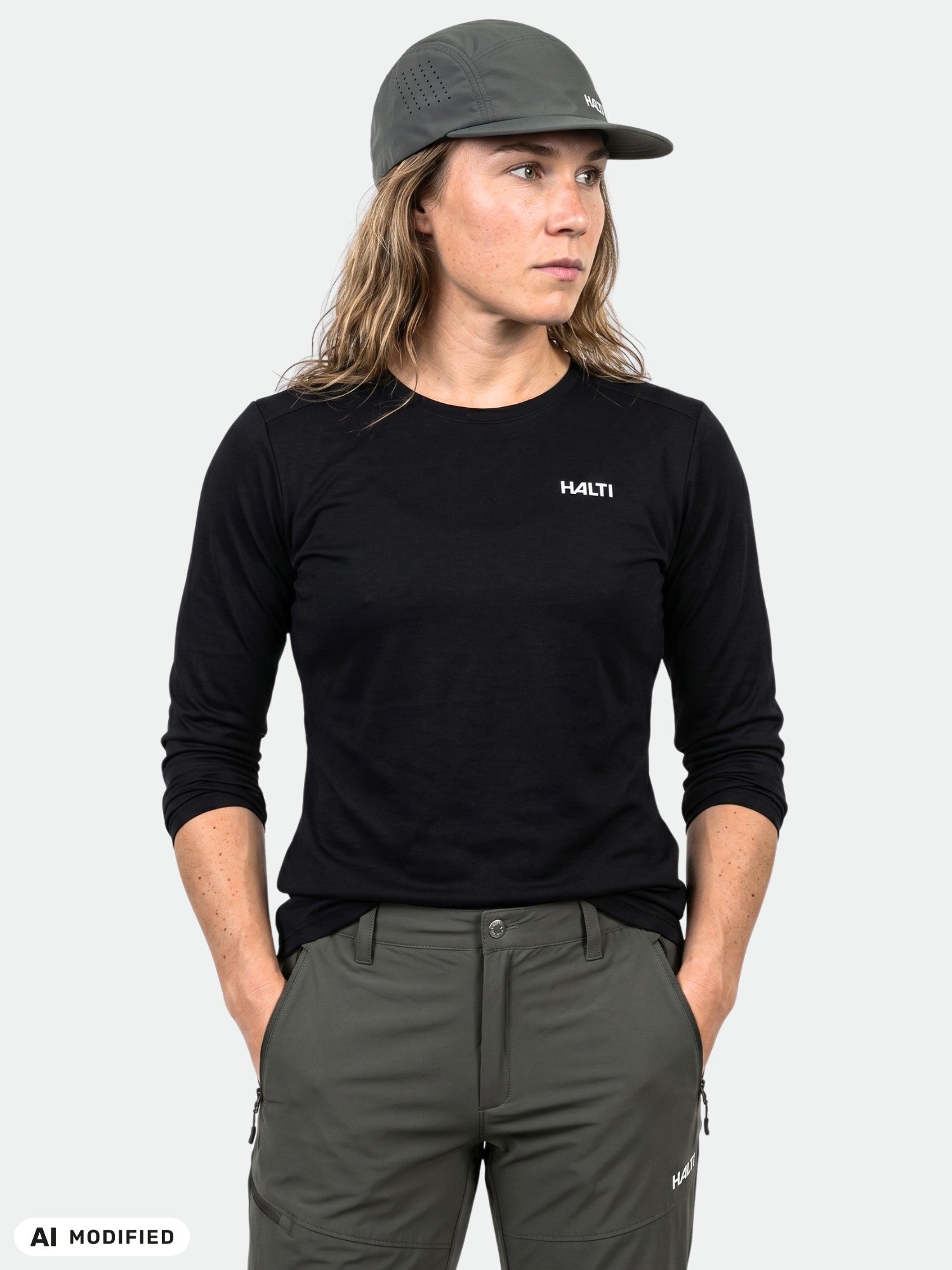 Eine Person in Outdoor-Kleidung posiert in einer olivfarbenen Hose und einer grauen Mütze und trägt dabei das Trainingsshirt „Salves“ von Halti für Damen.