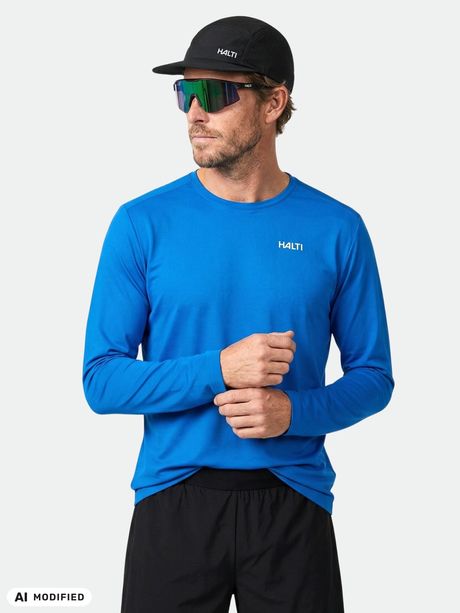 Ein Mann trägt vor einem schlichten weißen Hintergrund ein blaues „Halti Salves Trainingsshirt Herren“ aus recyceltem Polyester.