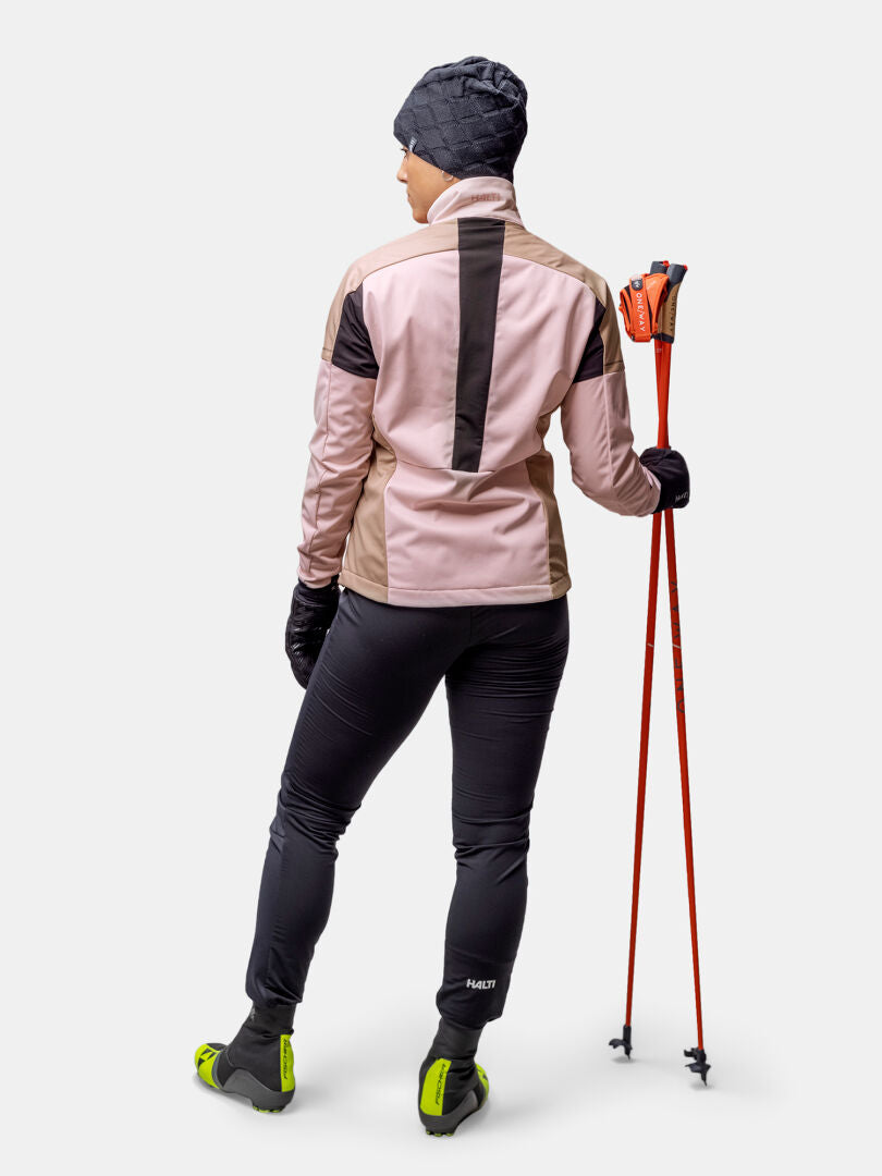 Eine Frau mit roten Skistöcken, die den Halti Huuru Langlaufanzug Damen trägt, ist bereit für den Langlauf.