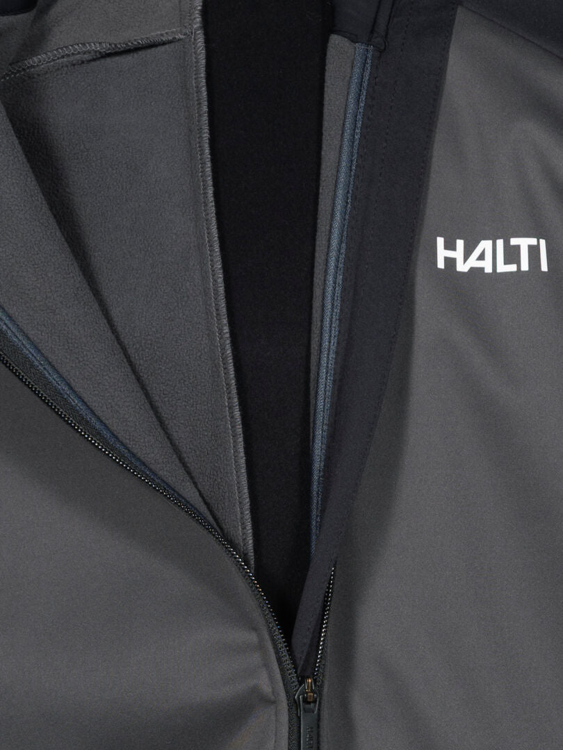 Nahaufnahme einer grauen Huuru Langlaufanzug Herren Jacke mit winddichtem Material, Halti Logo auf der Brust.