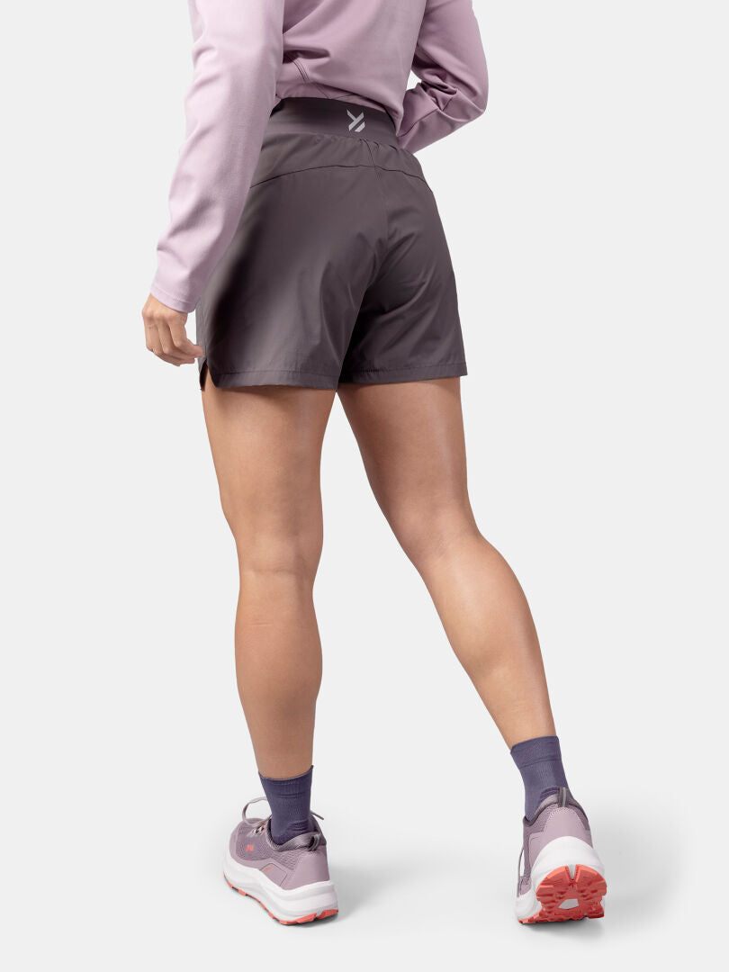 Person trägt Halti Uurto Shorts Damen, rosa Sweatshirt, Socken und rosa Sportschuhe.