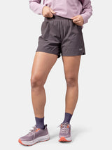 Person in einem lavendelfarbenen Sweatshirt, Halti Uurto Shorts Damen, lila Socken und lavendelfarbenen Laufschuhen auf weißem Hintergrund.