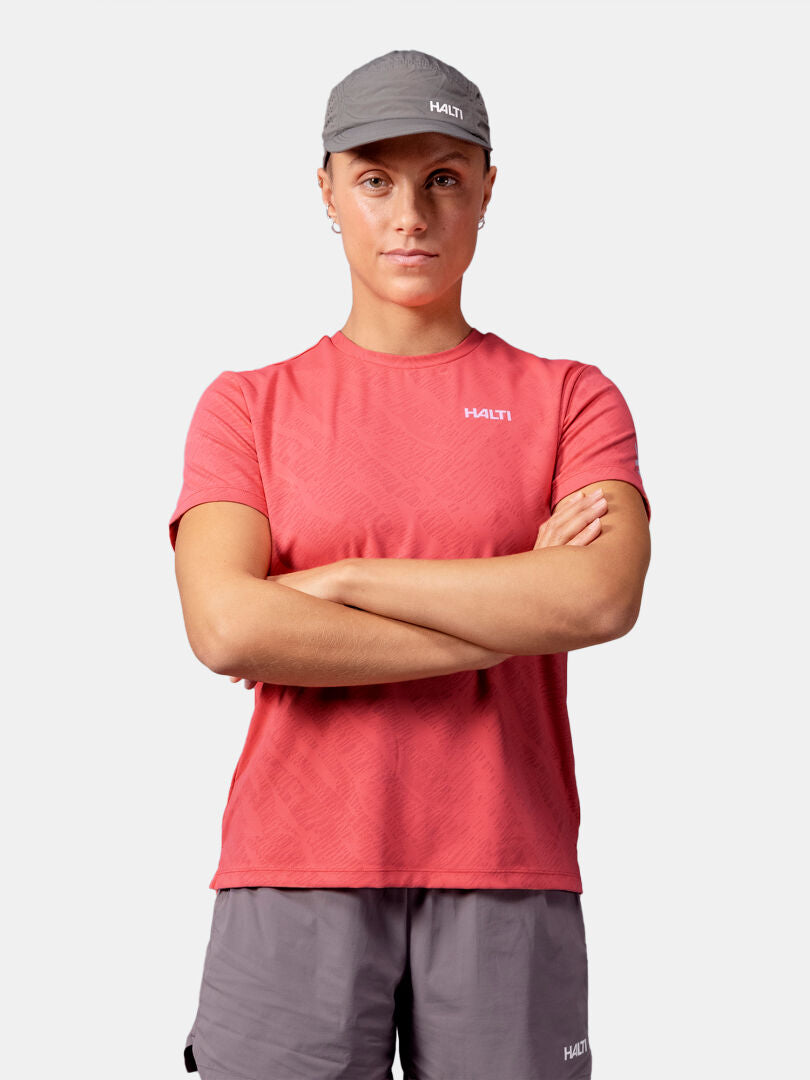 Stehende Person mit verschränkten Armen, die ein Halti Oulanka T-Shirt Damen und graue Shorts vor einem einfarbigen Hintergrund trägt.