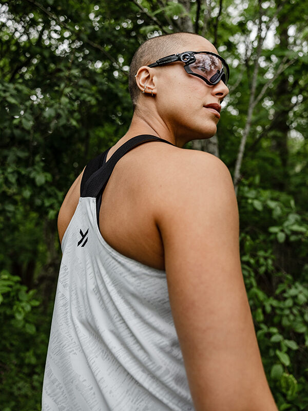 Eine Person mit rasiertem Haar in einem Halti Oulanka Trainingstop Damen und einer Schutzbrille steht im Freien und genießt den UPF 50+ Schutz.