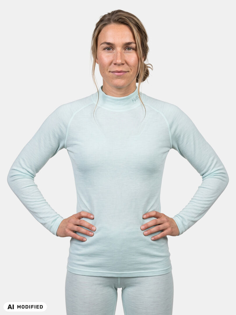 Eine Frau, die ein hellblaues Halti Neva Merino Unterwäsche-Set für Damen trägt – ein langärmeliges Baselayer-Oberteil mit Stehkragen.