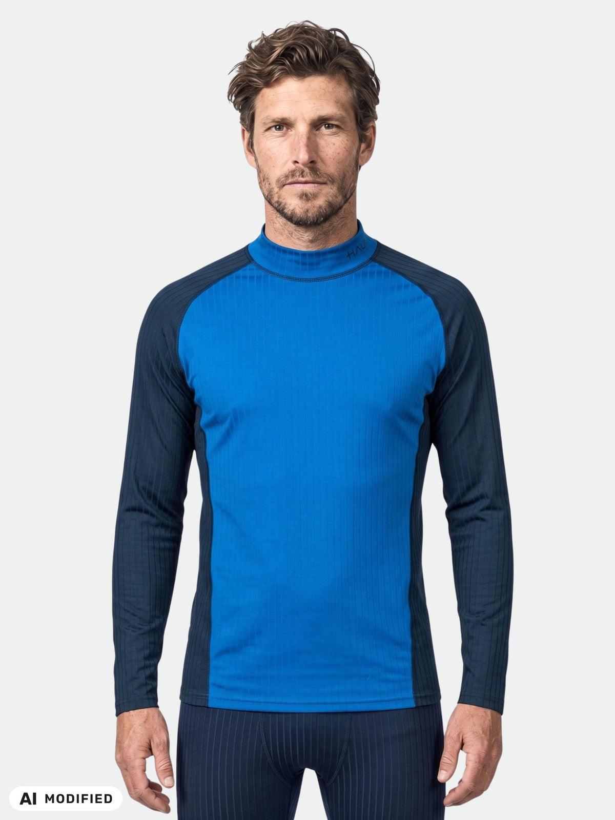 Mann im Halti Dual Baselayer Set für Herren (blau/schwarz), ideal zum Skifahren oder als Outdoor-Bekleidung, vor grauem Hintergrund.