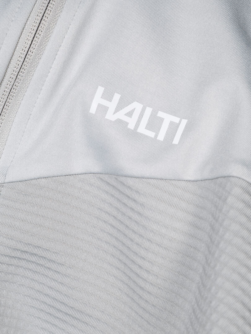 Nahaufnahme einer hellgrauen Halti HeatGrid Midlayer Jacke Herren mit Reißverschluss und weißem Halti-Logo auf der oberen Brust.