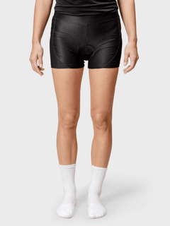 Stehende Person, die schwarze Halti Bike Rad Shorts Damen, weiße Socken und ein schwarzes Shirt vor einem hellen Hintergrund trägt.
