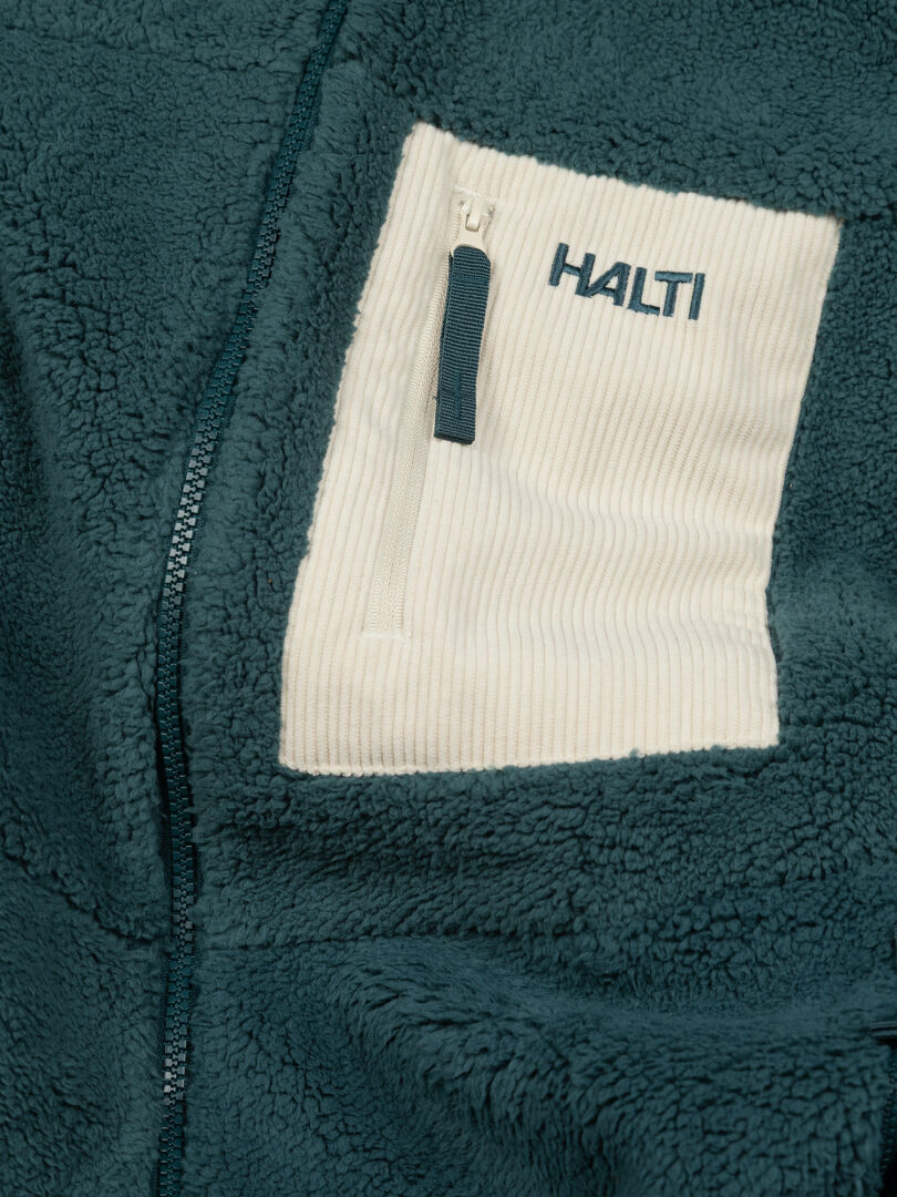 Nahaufnahme einer Halti Lumista Polar Fleecejacke für Damen in der Farbe Teal mit weißer Brusttasche, winddicht, ideal zum Wandern.