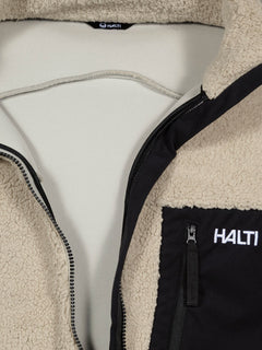 Nahaufnahme der Halti Lumista Polar Fleece Jacke Herren mit einer schwarzen Brusttasche mit Reißverschluss, die teilweise geöffnet ist, um das Futter zu zeigen.