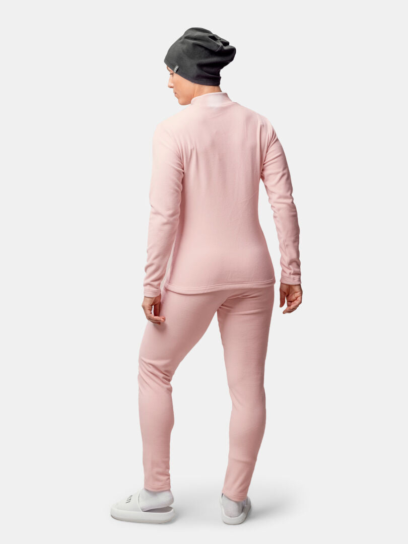 Frau mit Blickrichtung nach außen, bekleidet mit einem rosa Halti Trone Fleece-Shirt, passender Hose, grauer Mütze und weißen Schuhen.