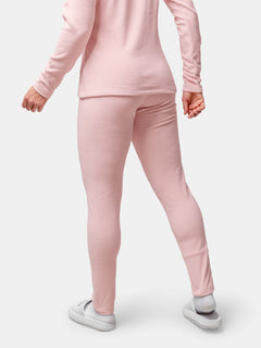 Person in Halti Trone Fleece-Hose Damen und passendem Oberteil mit weißen Hausschuhen, stehend vor einfarbigem Hintergrund.