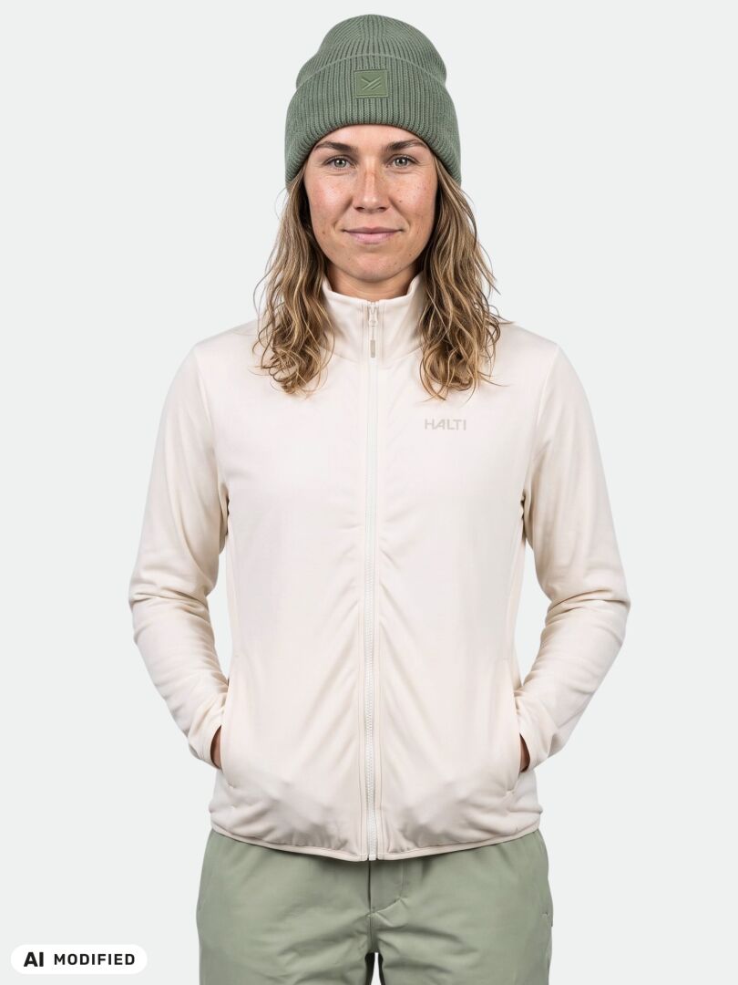 Person in einer Halti Rockmoon Fleecejacke für Damen, einer grünen Mütze und einer Hose, die nach vorne blickt und die Hände in den Taschen hat.