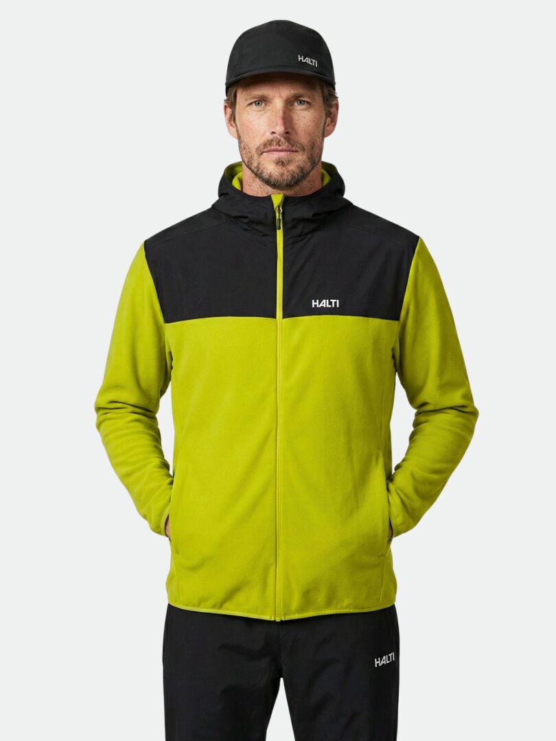 Ein Mann trägt die Halti Rockmoon Fleecejacke Herren und schwarze Hosen, die Hände in den Taschen.