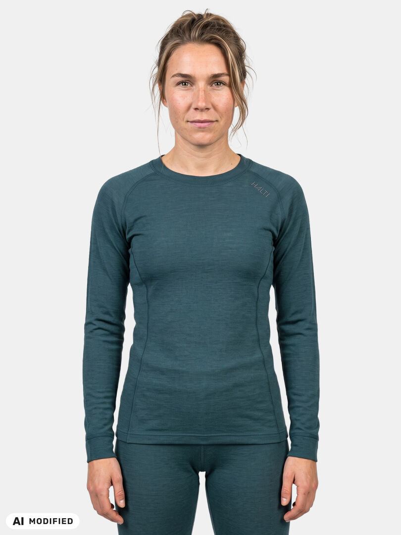 Eine Frau trägt das Halti Hossa II Merino-Unterwäsche-Set für Damen in der Farbe Teal und steht frontal vor einem weißen Hintergrund.