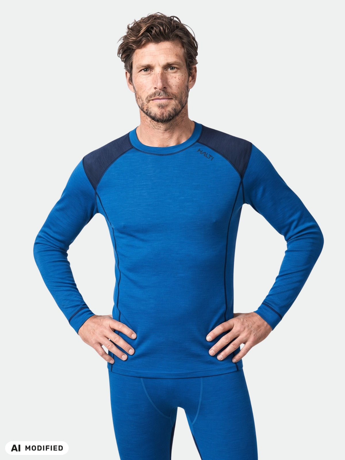 Ein Mann in einem „Halti Hossa II Merino“-Unterwäsche-Set für Herren, der vor einem einfarbigen, hellen Hintergrund steht.