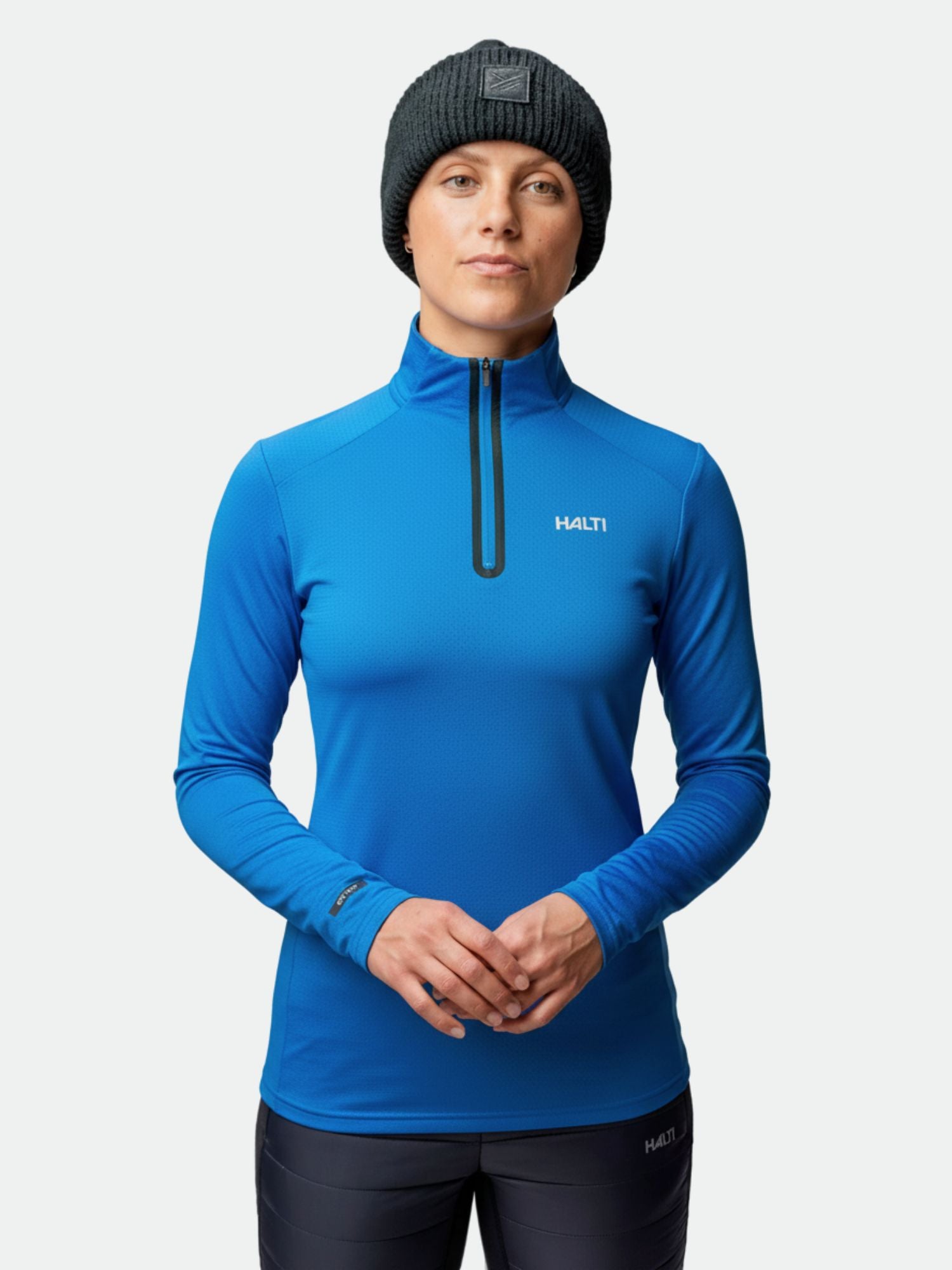 Eine Person trägt ein blaues Halti Jaako Hemd Damen Hemd und eine schwarze Mütze und steht vor einem schlichten Hintergrund.