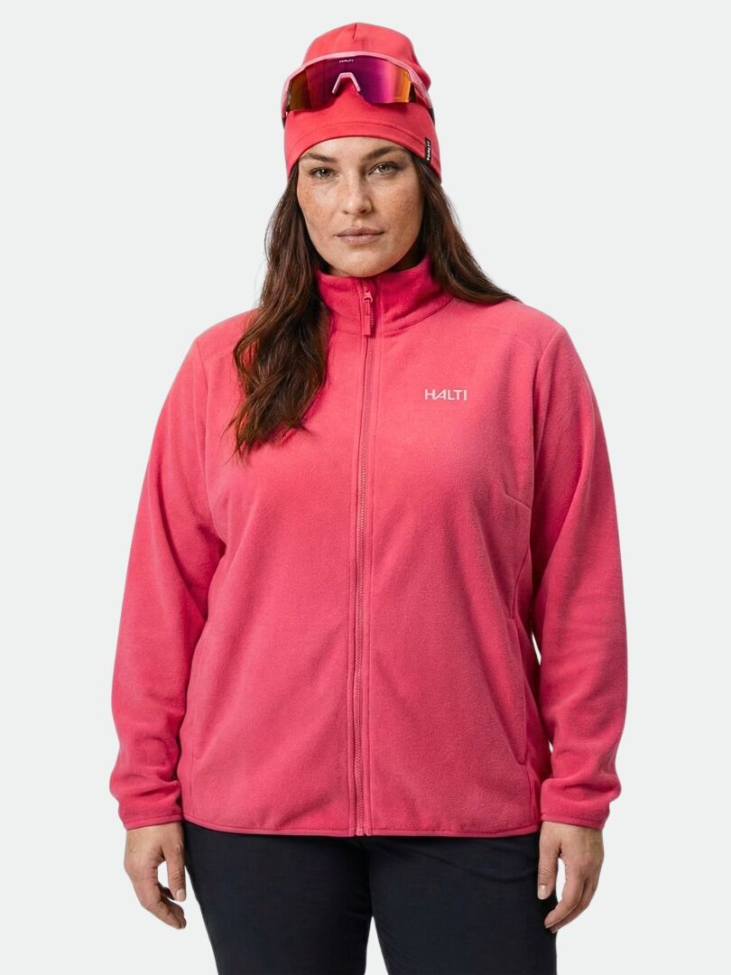 Frau in einer Halti Rockmoon Fleecejacke für Damen in Größe Plus, leuchtend pink, mit Mütze und Skibrille, die stilvoll dasteht.