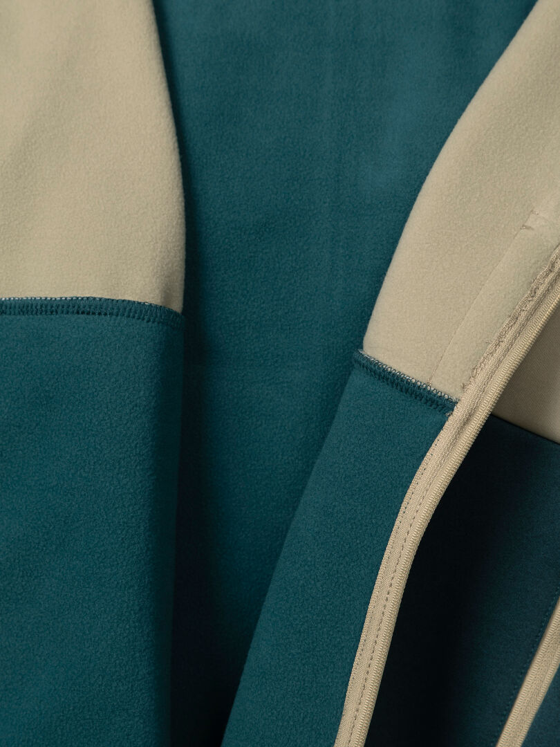 Nahaufnahme einer blaugrünen und beigen Halti Seiland Layer Jacke Damen-Fleecejacke mit Reißverschluss vorne und elastischem Zwischenfutter.