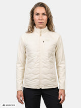 Eine Frau trägt eine cremefarbene Halti Suomis Hybrid Layer Jacke Damen mit gesteppter Vorderseite und einer Brusttasche mit Reißverschluss.
